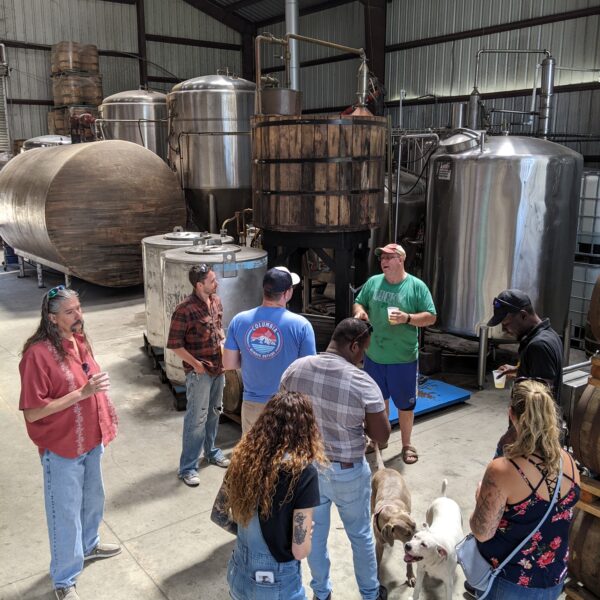 distillery tour with production equipment in background. dogs begging for attention.
