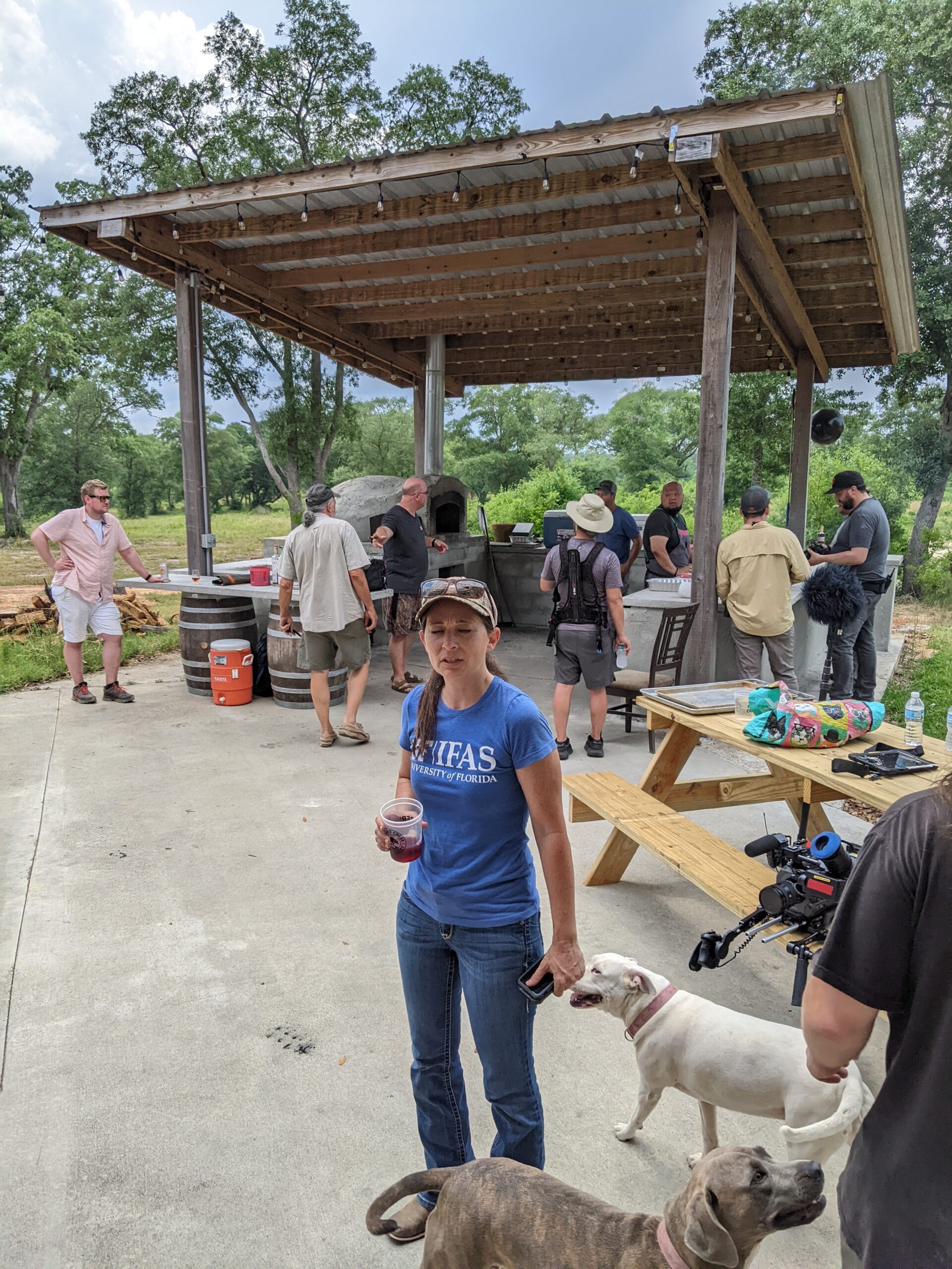 people standing around the pizza oven recording pork they killed that morning for a show