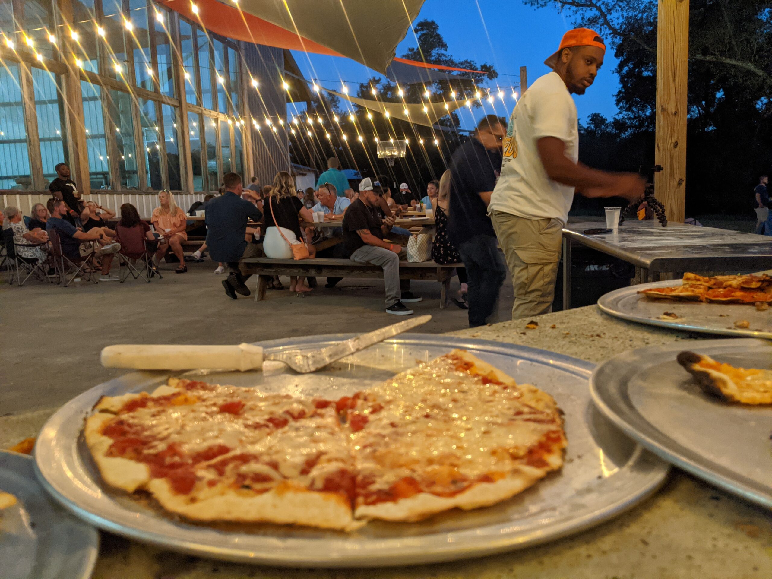 variety of pizzas with people having a good tome in the background.