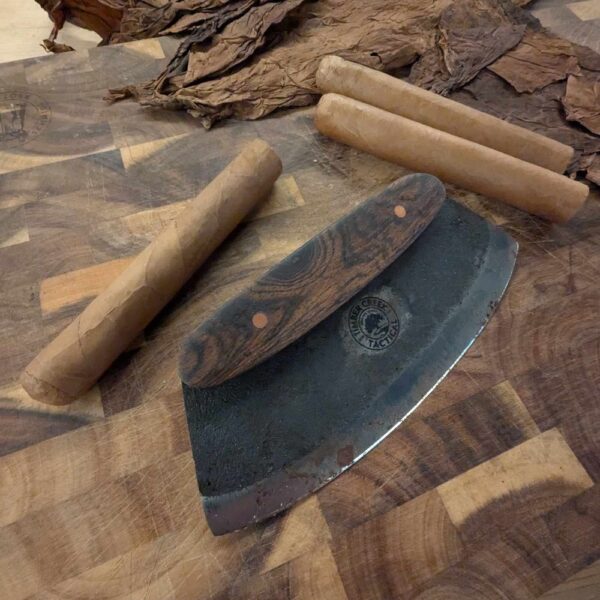 cigar with loose tobacco and chaveta on wooden cutting board
